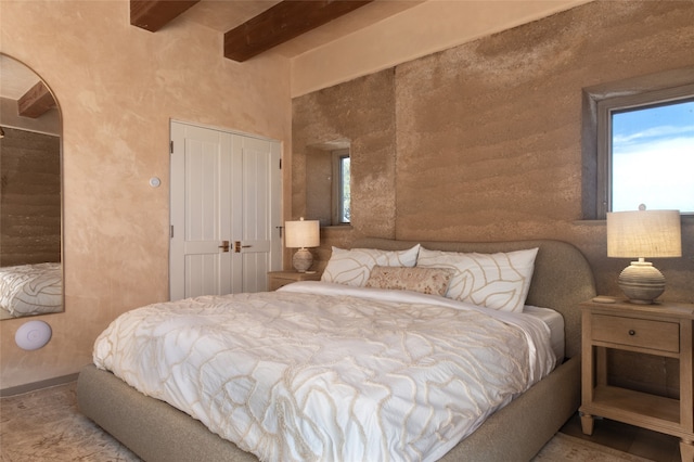 bedroom with a closet and beam ceiling