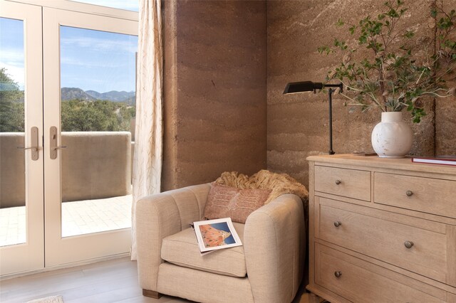 living area featuring light wood-type flooring, a mountain view, and french doors