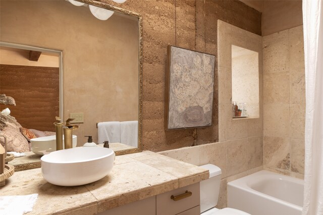 bathroom featuring a bathtub, tile walls, vanity, and toilet