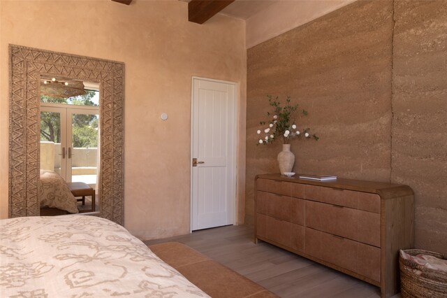 bedroom featuring wood-type flooring, french doors, beam ceiling, and access to outside