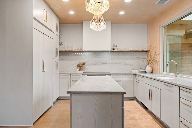 kitchen with white cabinetry, a center island, decorative light fixtures, sink, and a chandelier