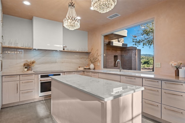 kitchen with sink, a notable chandelier, hanging light fixtures, backsplash, and oven