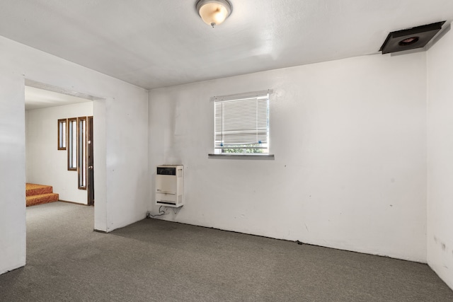 unfurnished room featuring heating unit and dark colored carpet