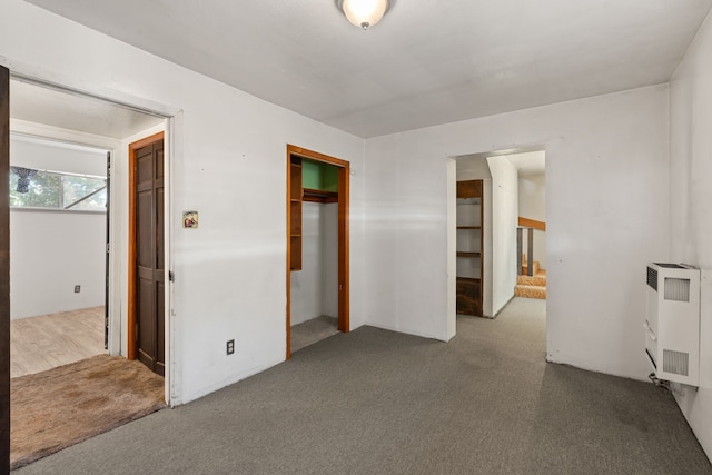 unfurnished bedroom featuring heating unit, a closet, and carpet floors