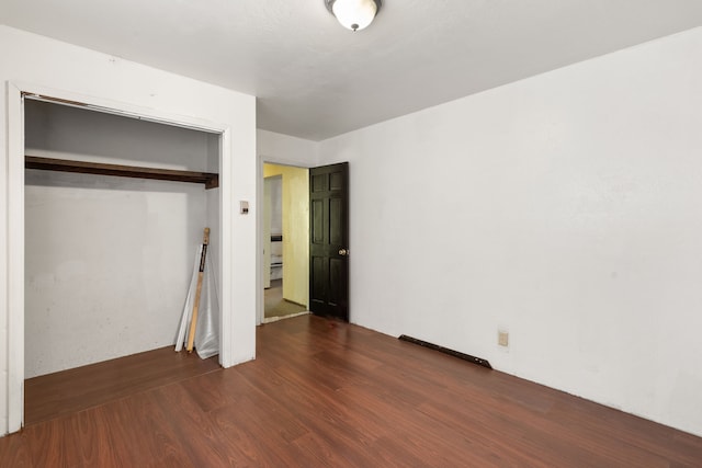 unfurnished bedroom featuring a closet and dark hardwood / wood-style flooring