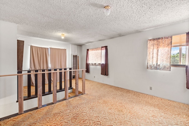 carpeted spare room with a textured ceiling and a wealth of natural light