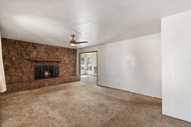 unfurnished living room featuring a textured ceiling, a fireplace, carpet flooring, and ceiling fan