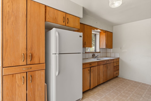 kitchen with decorative backsplash, white refrigerator, and sink