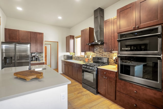 kitchen featuring a sink, light countertops, appliances with stainless steel finishes, backsplash, and wall chimney exhaust hood