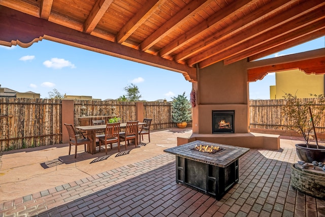 view of patio / terrace with outdoor dining space, a large fireplace, and a fenced backyard