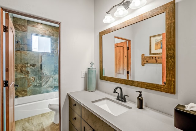 bathroom with toilet, combined bath / shower with glass door, and vanity