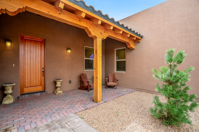 view of exterior entry featuring a patio area, a tiled roof, and stucco siding