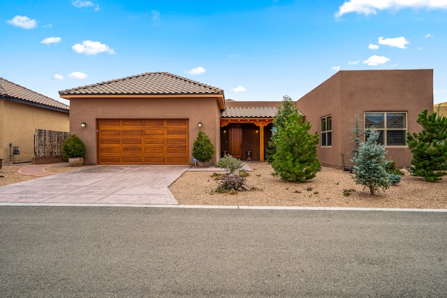 view of front facade with driveway, an attached garage, a tiled roof, and stucco siding