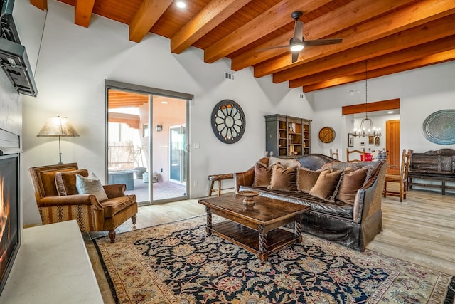 living room featuring beam ceiling, wood ceiling, ceiling fan with notable chandelier, and light wood-type flooring