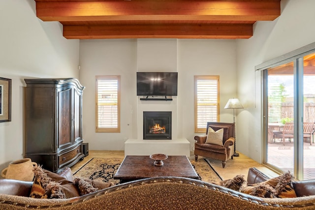 living area with wooden ceiling, wood finished floors, beamed ceiling, and a glass covered fireplace