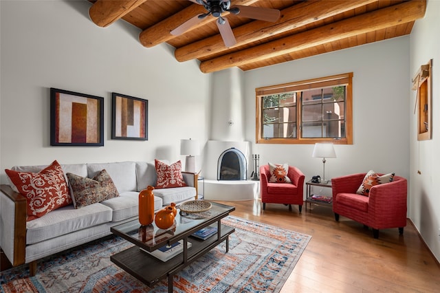 living room with wood ceiling, light hardwood / wood-style floors, beamed ceiling, a large fireplace, and ceiling fan