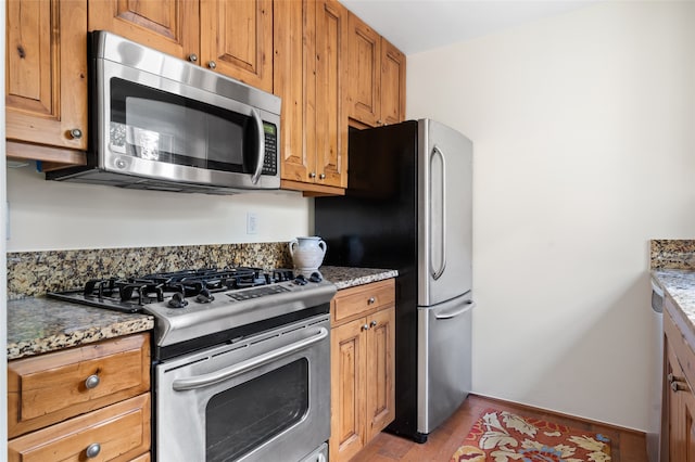 kitchen with stone counters, light hardwood / wood-style flooring, and stainless steel appliances