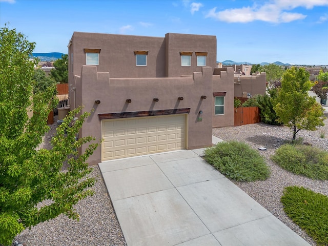 southwest-style home featuring a mountain view, driveway, an attached garage, and stucco siding