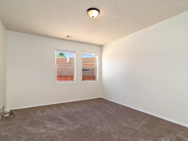 carpeted spare room with a textured ceiling, visible vents, and baseboards