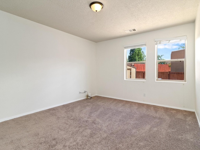 carpeted empty room with visible vents, baseboards, and a textured ceiling