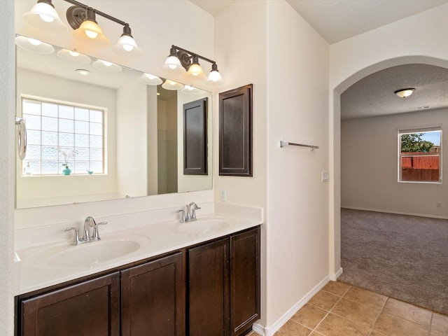 bathroom with double vanity, a sink, baseboards, and tile patterned floors