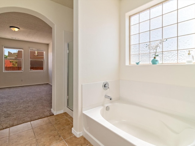 bathroom featuring a healthy amount of sunlight, a textured ceiling, a shower stall, and a garden tub