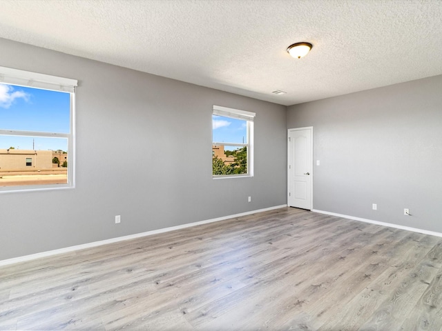 empty room with a textured ceiling, wood finished floors, and baseboards