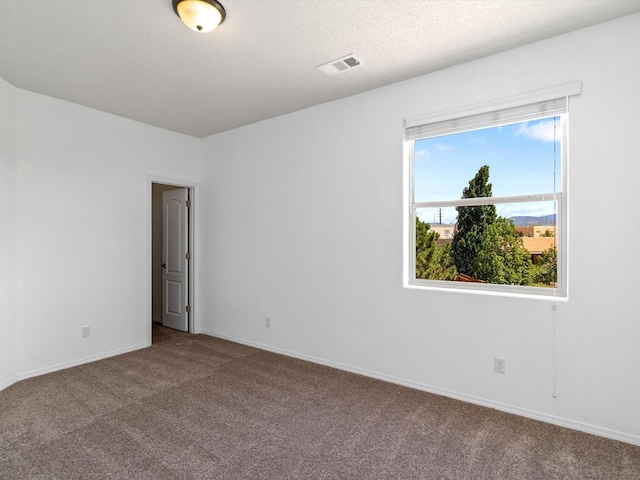 carpeted empty room with baseboards, visible vents, and a textured ceiling