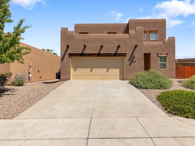 southwest-style home with a garage, fence, concrete driveway, and stucco siding