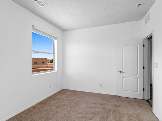 unfurnished room featuring visible vents, a textured ceiling, and carpet flooring