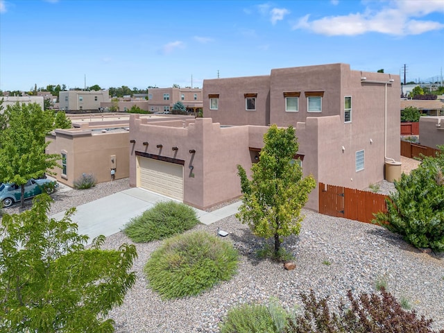 view of front facade featuring stucco siding, an attached garage, a gate, fence, and driveway