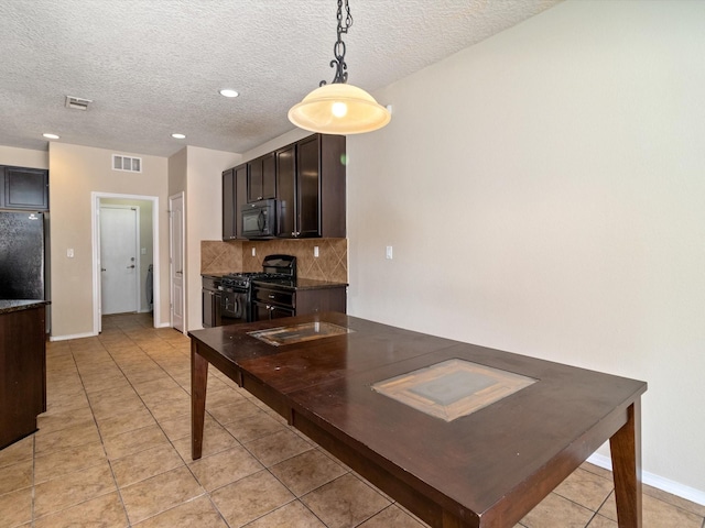 kitchen with visible vents, freestanding refrigerator, decorative backsplash, black microwave, and range with gas cooktop