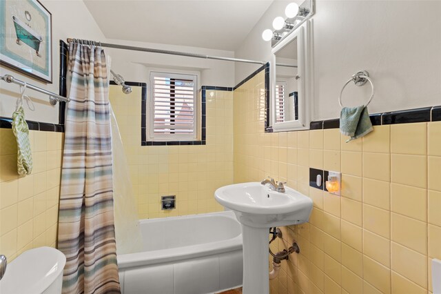 bathroom featuring tile walls, shower / bath combo, and toilet