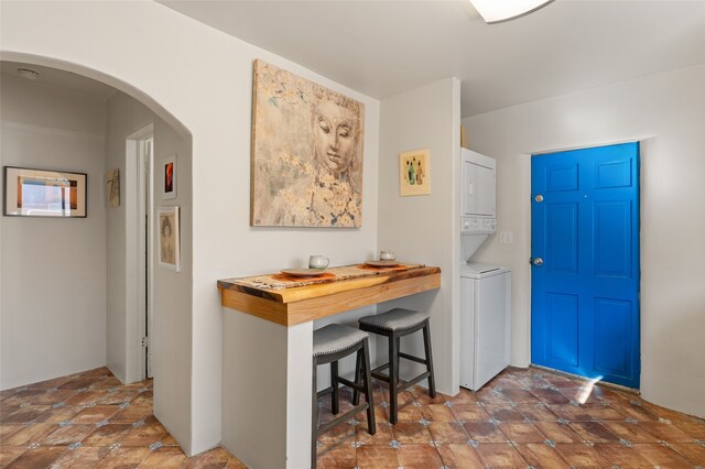 entryway featuring dark tile patterned flooring and stacked washing maching and dryer