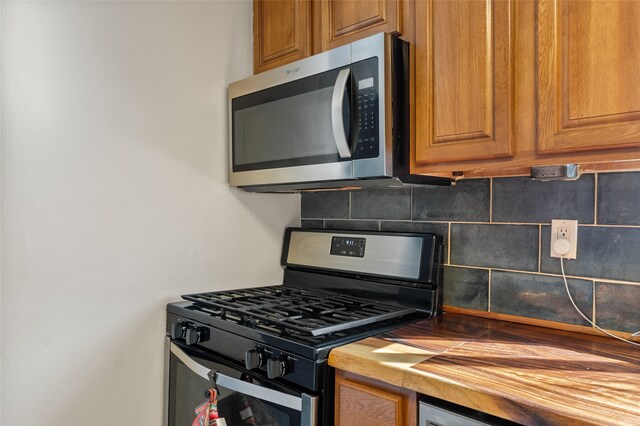 kitchen with decorative backsplash, appliances with stainless steel finishes, and wooden counters