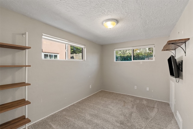 empty room with light carpet and a textured ceiling