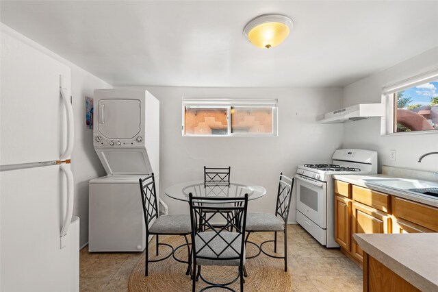 kitchen with light tile patterned floors, sink, white appliances, stacked washer and clothes dryer, and extractor fan