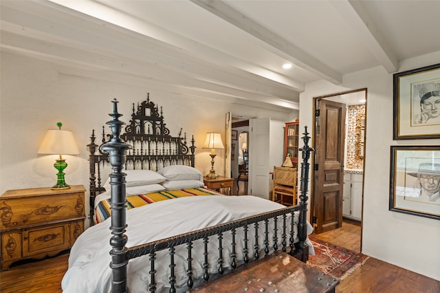 bedroom featuring hardwood / wood-style flooring, connected bathroom, and beam ceiling