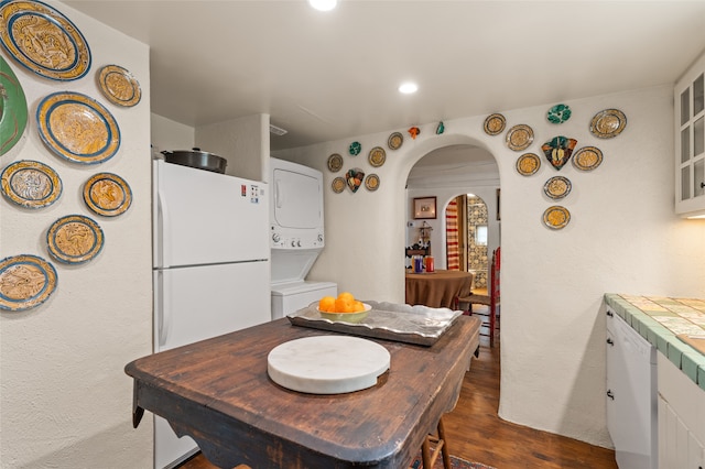 dining area featuring stacked washing maching and dryer and dark wood-type flooring