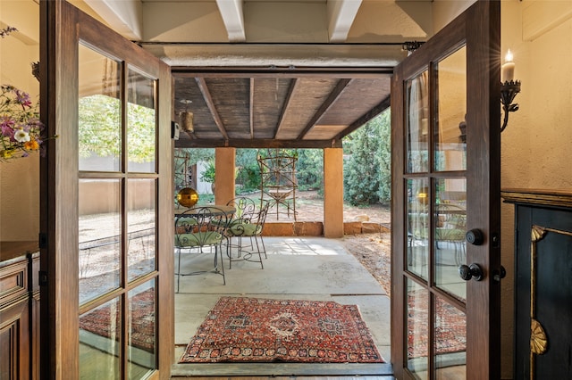 doorway to outside featuring beamed ceiling