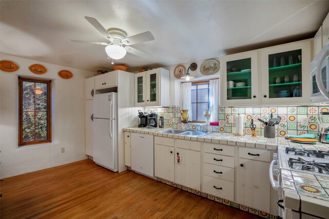 kitchen with white cabinets, sink, white appliances, tile countertops, and decorative backsplash