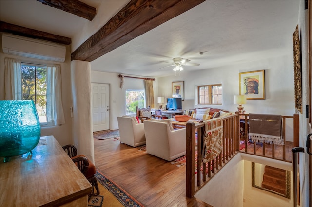 living room featuring light hardwood / wood-style flooring, beam ceiling, ceiling fan, and a wealth of natural light