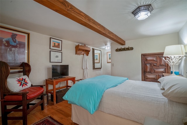 bedroom with beamed ceiling and hardwood / wood-style flooring