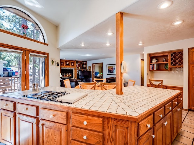 2176 La Tierra, Los Alamos, NM 87544 - kitchen with open shelves, tile counters, white cooktop, recessed lighting, and a glass covered fireplace