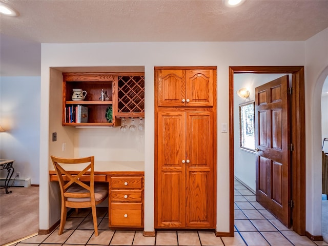 2176 La Tierra, Los Alamos, NM 87544 - office area featuring light tile patterned floors, baseboards, arched walkways, built in desk, and a baseboard heating unit