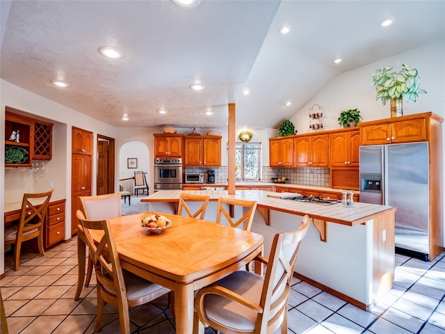 tiled dining area featuring a textured ceiling and vaulted ceiling