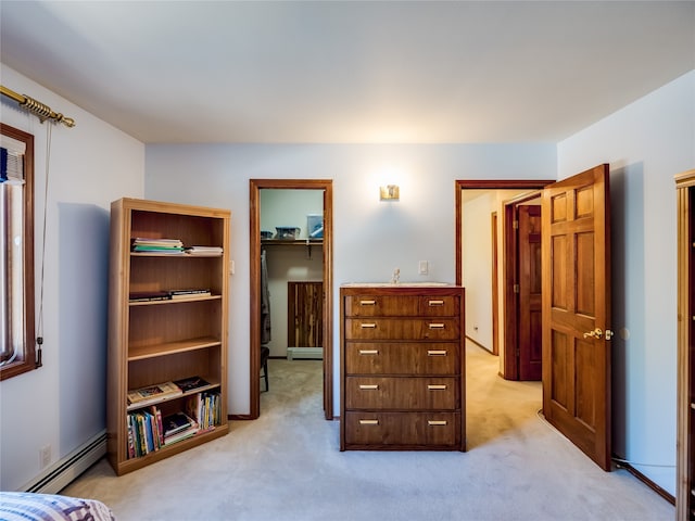 carpeted bedroom featuring a baseboard radiator, a closet, and a walk in closet