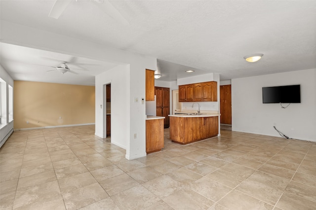 unfurnished living room featuring a textured ceiling, sink, and ceiling fan