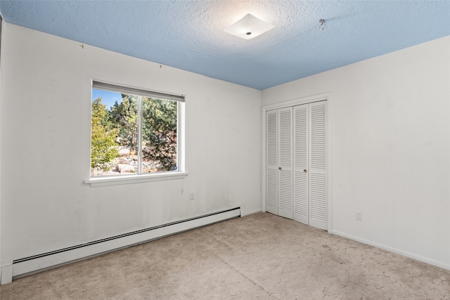 unfurnished bedroom with light carpet, a baseboard heating unit, a closet, and a textured ceiling