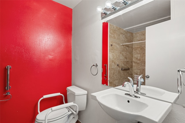 bathroom featuring tiled shower, toilet, and sink